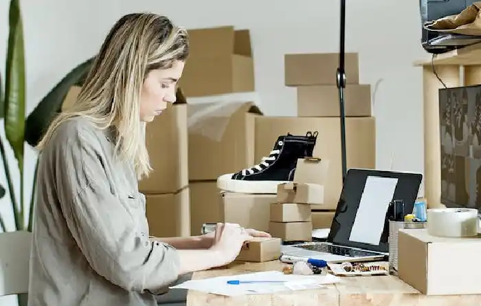 Female online store business owner packing ecommerce shipping box.