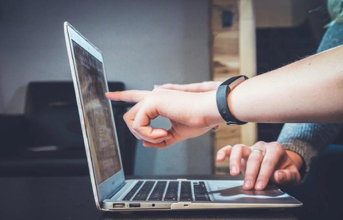 Two people pointing at a laptop using AI and analytics for a contact center